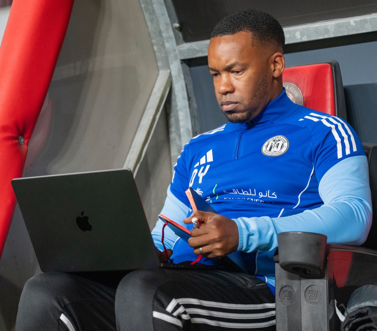 Dazell Young working on a laptop in the Al Jazira dugout